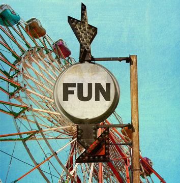 aged and worn vintage photo of ferris wheel with fun sign