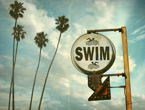 aged and worn vintage photo of swim sign at beach