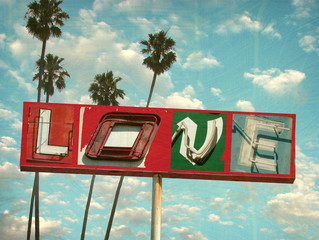 aged and worn vintage photo of neon love sign with palm trees