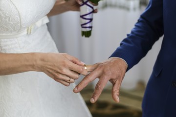 bride's hand putting a wedding ring on the groom's finger