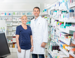 Fototapeta na wymiar Confident Pharmacist And Assistant Standing In Pharmacy
