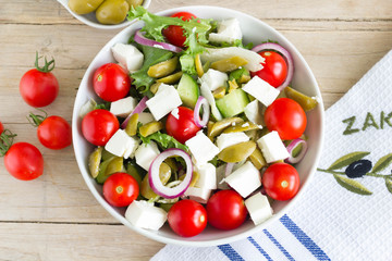 Greek salad on a wooden table, up view.