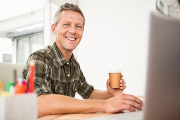 Smiling casual businessman working and having coffee