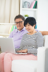 Senior Couple Sitting On Sofa Using Digital Tablet