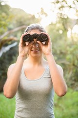 Smiling pretty brunette looking through binoculars