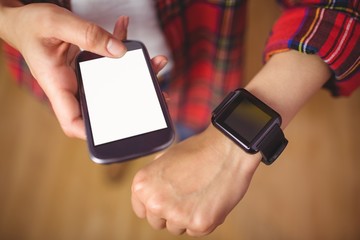 Pretty hipster using her smartphone and smartwatch