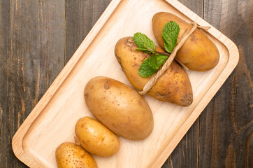 Raw potatoes on wooden plate