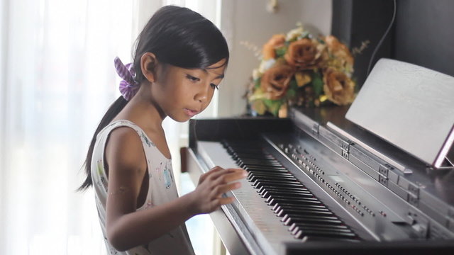 Asian girl learning to play piano
