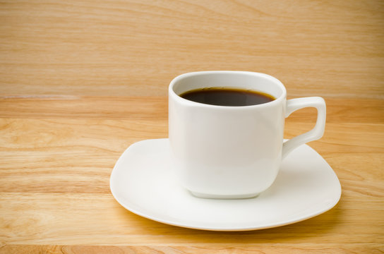 The cup of hot coffee on wooden background