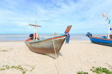 Naklejka na ściany i meble Wooden fishing boat on the beach with blue sky