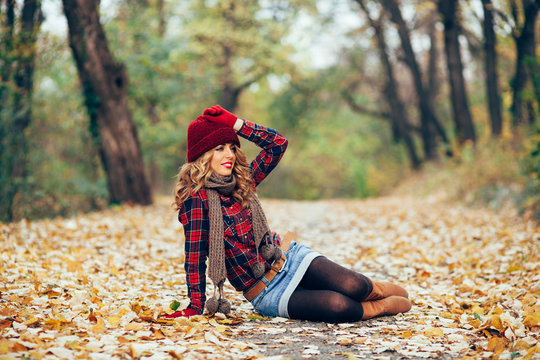 Beautiful woman sitting in fallen leaves