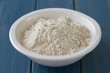 powder on white plate on blue wooden background