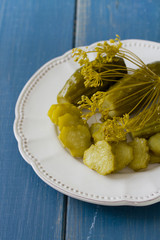 salted cucumbers on white plate on blue wooden background