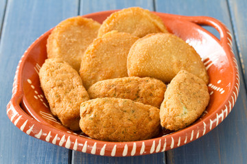meat and cod fish croquete on dish on blue background