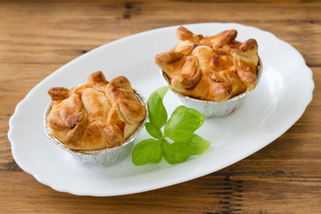 pie with chicken with basil on white plate on brown wooden background