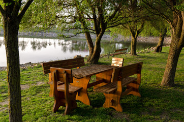 Empty wooden table and chairs near the lake