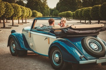 Wealthy couple in classic convertible - obrazy, fototapety, plakaty