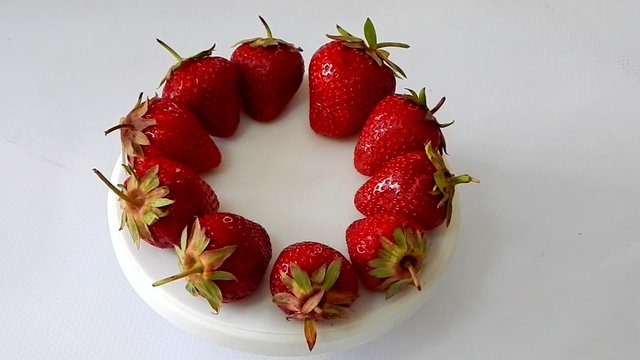 Juicy strawberries on white plate studio shot