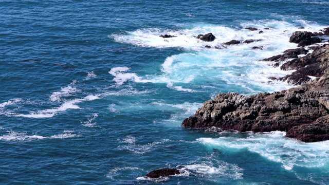 Coastline in Big Sur. Pacific Ocean waves against cliffs. Blue water and sunny day. 