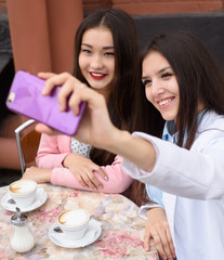 Obraz na płótnie Canvas Happy Young asian women making selfie photo on smartphone