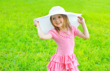 Portrait of little girl in dress and straw hat in summer day