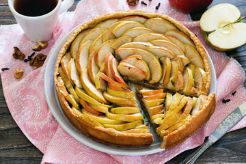 Apple tart, shortcrust pastry pie with walnuts on a wooden backg