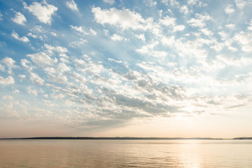 Fototapeta premium Clouds and sun rays over lake at sunrise