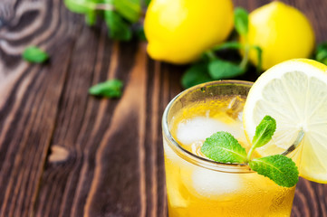 Two glasses of ice tea with ice-cubes on wooden table
