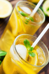 Two glasses of ice tea with ice-cubes on wooden table