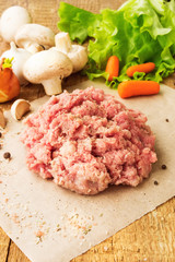 Fresh raw minced meat on wood table, with vegetables