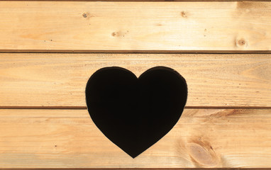 hole in the shape of heart. a hole in the shape of a heart on a wooden background