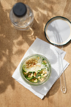 Home prepared healthy snack of zucchini, Parmesan cheese and pine nuts in jar on wooden background