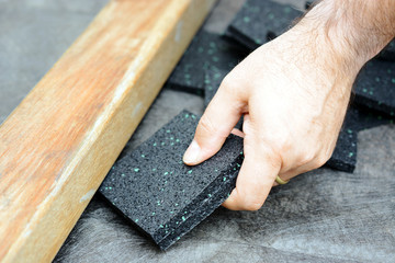Schreiner oder Handwerker setzt Granulatpad aus Bautenschutzmatte unter Holzbalken für Terrasse 
