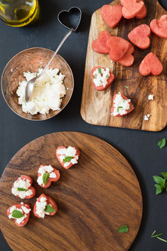 Summer appetizer of heart-shaped watermelon with feta cheese and rosemary or mint leaves. Selective focus