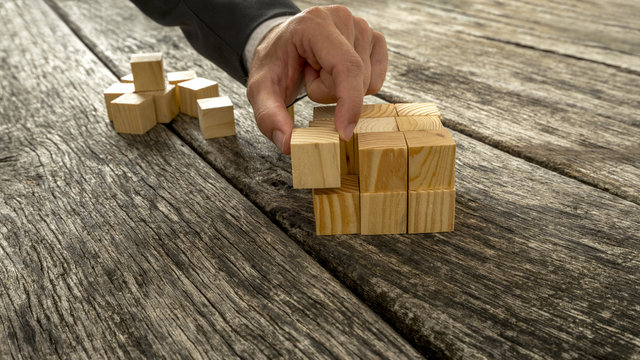 Closeup of businessman assembling blank wooden cubes into a stru