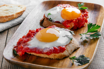 fried eggs with tomato sauce on bruschetta