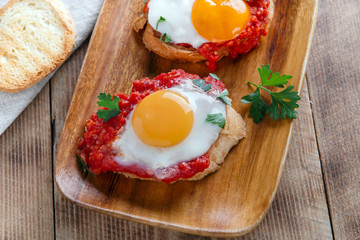 fried eggs with tomato sauce on bruschetta