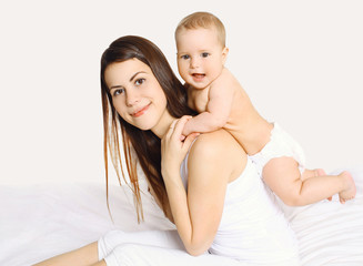 Happy young mother playing with baby on the bed at home
