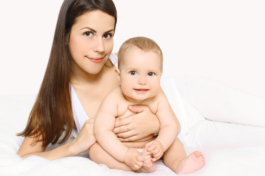 Portrait of cute baby and mother together on the bed