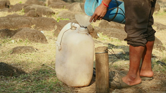 toddy-tapper pouring freshly harvested palm sap in a plastic jerrycan using a funnel