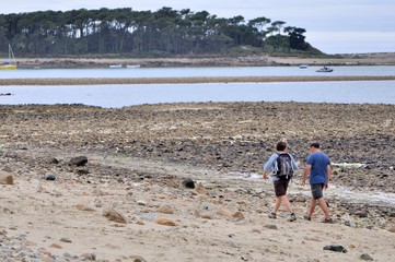 Couple de randonneurs marchant sur une plage en Bretagne