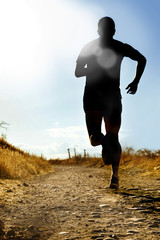 full body silhouette of extreme cross country man running on rural track jogging at sunset