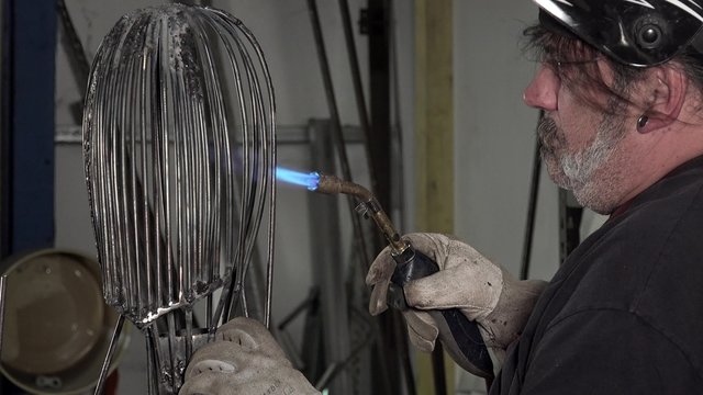 a sculptor arc working on his statue/twisting and welding metal parts
