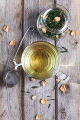 Mug of flavored green tea with rose buds and petals