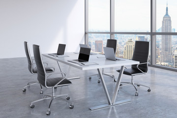 Modern meeting room with huge windows looking at New York City. Black leather chairs and a white table with laptops. 3D rendering.