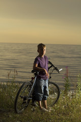 Fototapeta premium boy on a bicycle near the sea in the evening at sunset.