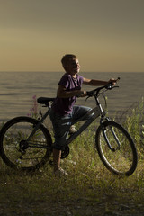 young boy with a bicycle in nature rests.