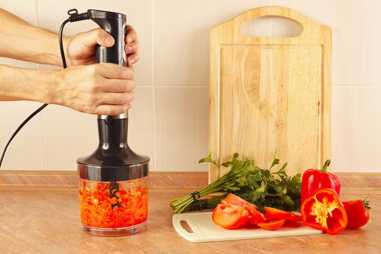 Hands chefs chopped red paprika in a blender