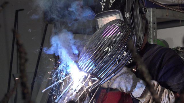 a sculptor arc working on his statue/twisting and welding metal parts
