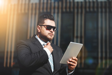 Portrait of business man reads news on tablet while standing in